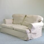 A tan upholstered three seater sofa, with loose covers,