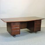 A 1950's mahogany pedestal desk, having a curved rectangular top and eight short drawers below,