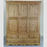 A modern pine triple wardrobe, with drawers beneath,