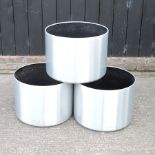 A set of three brushed aluminium pots,