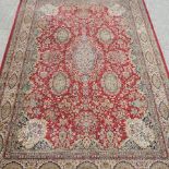 A large woollen rug, with floral designs, on a red ground, within multiple borders,