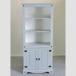 A pale blue painted open bookcase, with a cupboard below,