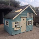 A green painted wooden children's play cottage, partly furnished,
