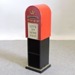 A red painted wooden shelf, in the form of a postbox,