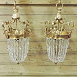 A pair of scrolled gilt metal mounted chandeliers, with glass drops,