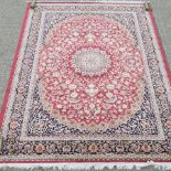 A Keshan carpet, with a central medallion and floral designs, on a red ground,