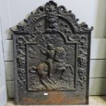 A black painted cast iron fire back, 56cm, relief decorated with a figure on horseback,