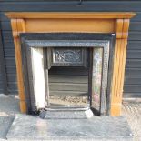 A black painted cast iron and tiled fire insert, with a pine surround,