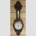 A late 19th century carved oak cased aneroid barometer,