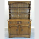 A mid 20th century oak dresser, the plate rack above cupboards,