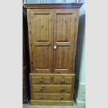 A modern pine single wardrobe, with drawers beneath,