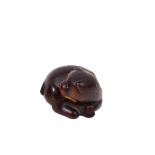 A JAPANESE WOOD NETSUKE OF A PUPPY, 19TH CENTURY carved in recumbent pose, playing with a ball of