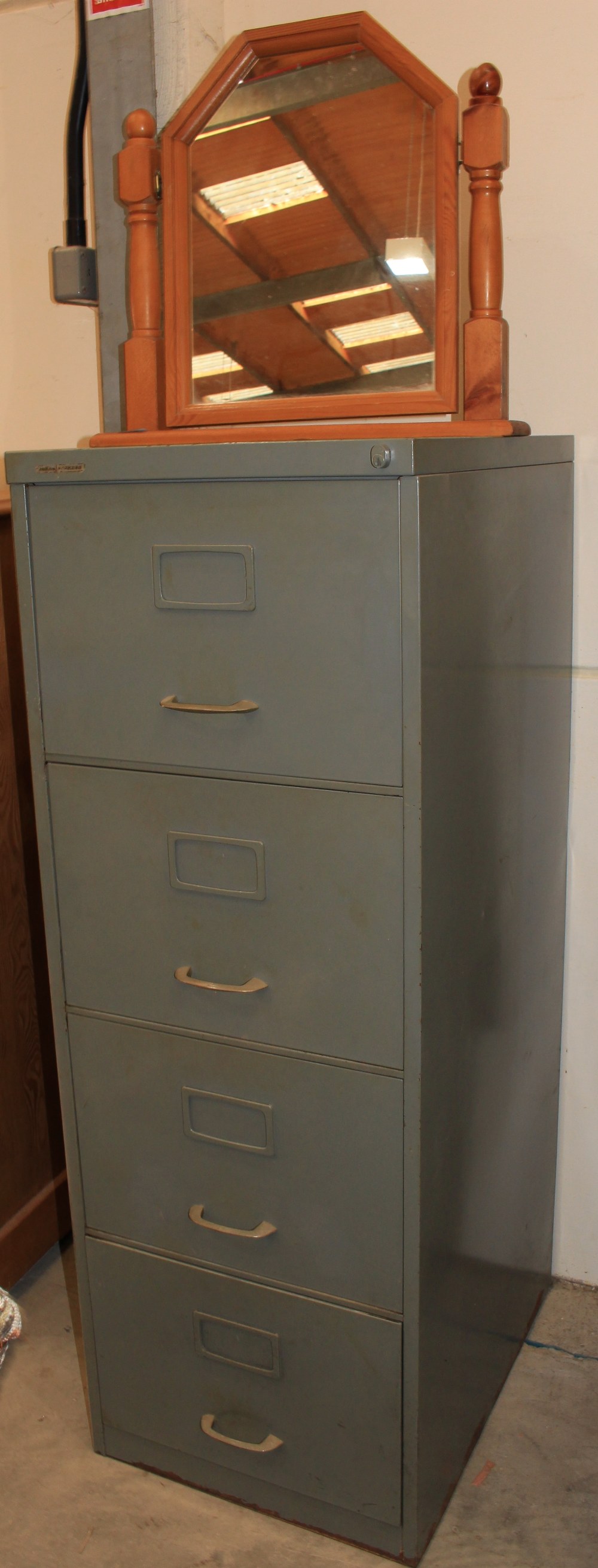 A metal filing cabinet and a dressing mirror