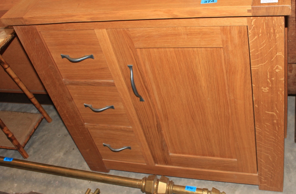 A 'Next' oak cabinet with three drawers. 31 ½" wide