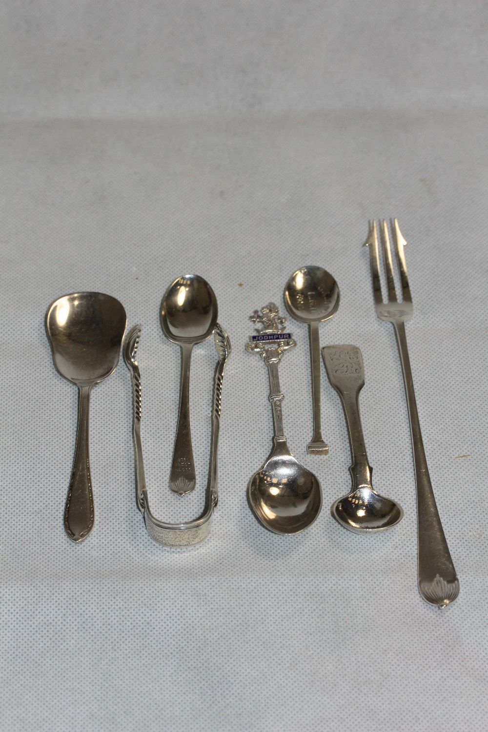 Silver smallware comprising a sugar bow, pickle fork and five spoons. 4ozs