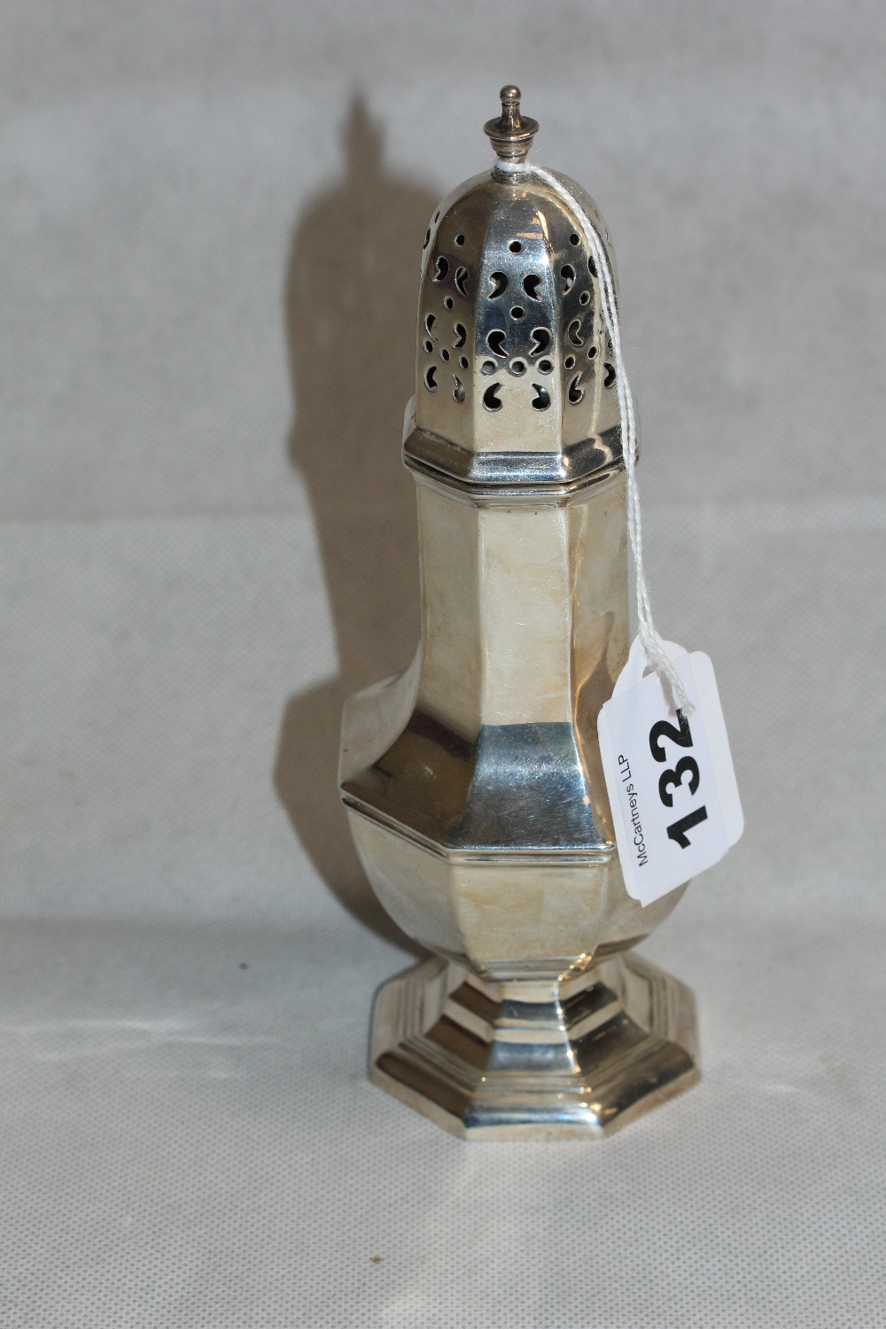 A George V silver sugar caster of octagonal design by Walker and Hall. 7 ½" high. Sheffield 1930.