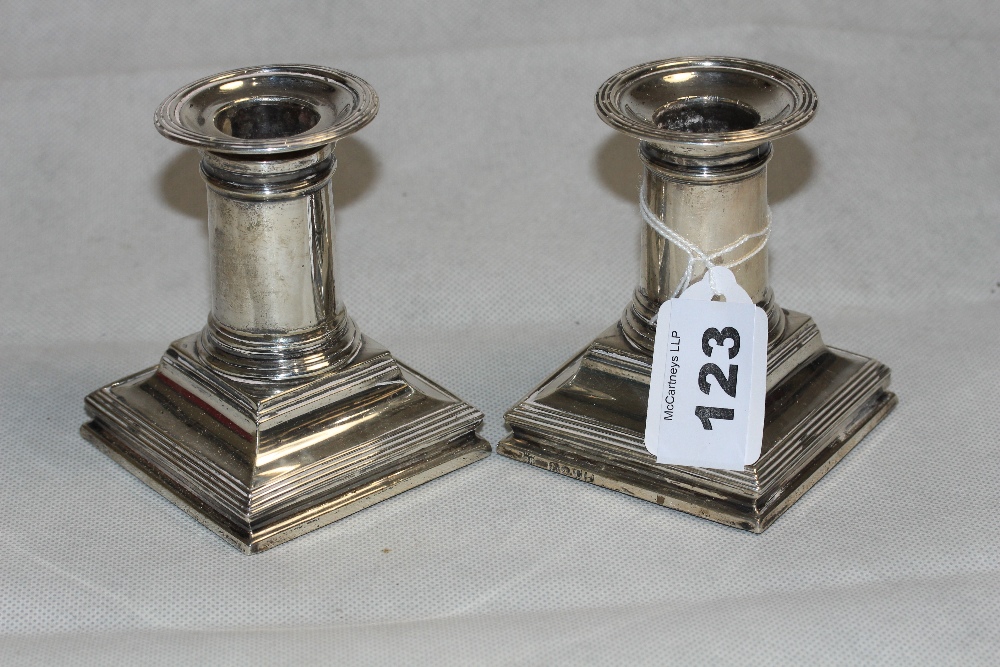 A pair of Victorian silver squat candlesticks with reeded drip trays and downswept square bases.