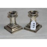 A pair of Victorian silver squat candlesticks with reeded drip trays and downswept square bases.
