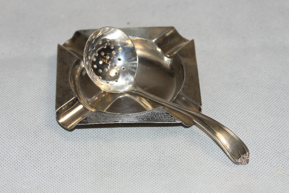 A silver engine turned ashtray Birmingham 1936 and a silver sifter spoon, Sheffield 1929. 1oz