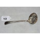 A George III silver sifting spoon, the repoussé bowl decorated with fruit, foliate bright cut