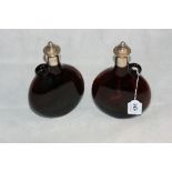 A pair of Victorian amber glass flasks with silver mounted necks and cork stoppers. 9" high.
