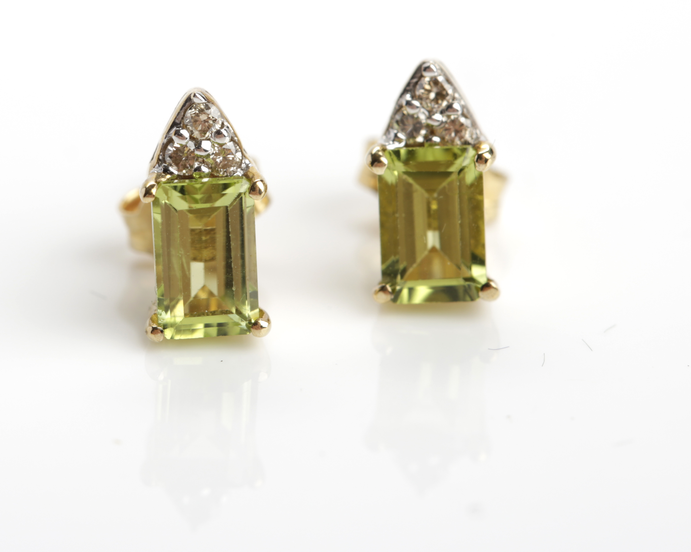 PAIR OF PERIDOT AND DIAMOND STUD EARRINGS each with an emerald cut peridot 6mm x 4mm set below