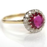 RUBY AND DIAMOND CLUSTER RING with a central round ruby, surrounded by diamonds,