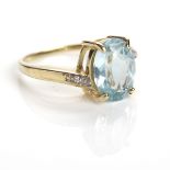 AQUAMARINE AND DIAMOND RING with a central oval aquamarine on diamond set shoulders,