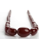 CHERRY BAKELITE NECKLACE formed of graduated ovoid beads, the largest bead 30mm long,