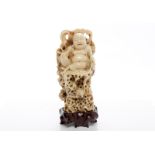 EARLY 20TH CENTURY CHINESE IVORY CARVING of a seated Buddha on a naturalistic coral-like seat,