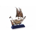 WHITE METAL MODEL OF AN ARAB DHOW fitted to a felt covered wedge shaped base,