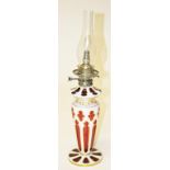 A 19TH CENTURY BOHEMIAN RUBY AND CREAM GLASS OIL LAMP, 
with glass reservoir and vase shaped stem,