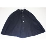 AN OLD BLACK POLICE CAPE, 
with silver plated buttons and metal clasp in the form of two shamrocks,