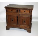 A HEAVY OAK AND EBONISED CUPBOARD, in the 17th Century style,