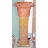 A TERRACOTTA GARDEN URN, together with an associated fluted composition stone plinth,
