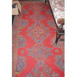 A RED GROUND TURKISH WOOL CARPET, with five medallions, within a banded border,