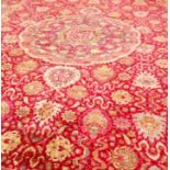 A LARGE ORIENTAL STYLE CARPET, the crimson ground with a large circular medallion,