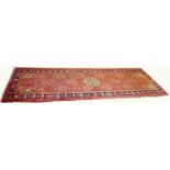AN ATTRACTIVE PERSIAN RUNNER, the iron red ground with a central star shaped ivory medallion,