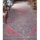 A SEMI ANTIQUE PERSIAN STYLE CARPET, with large diamond shaped medallion, with red ground,