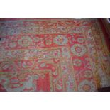 A LARGE TURKISH WOOL CARPET, the faded iron red ground with rows of various medallions,
