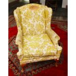 A MODERN WING ARMCHAIR, covered in gold and ivory fabric, and raised on front cabriole legs.