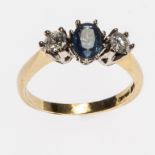 A THREE-STONE SAPPHIRE AND DIAMOND RING, the central .50ct oval sapphire, flanked with two .