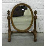 A VICTORIAN OVAL WALNUT DRESSING TABLE MIRROR, with fluted supports, and urn finials,