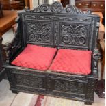 A 17TH CENTURY STYLE EBONIZED OAK MONK'S BENCH, with carved double panel back,