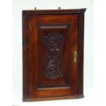 AN EDWARDIAN CARVED WALNUT CORNER CUPBOARD, WITH CARVED PANEL TO THE DOOR, 46CM W