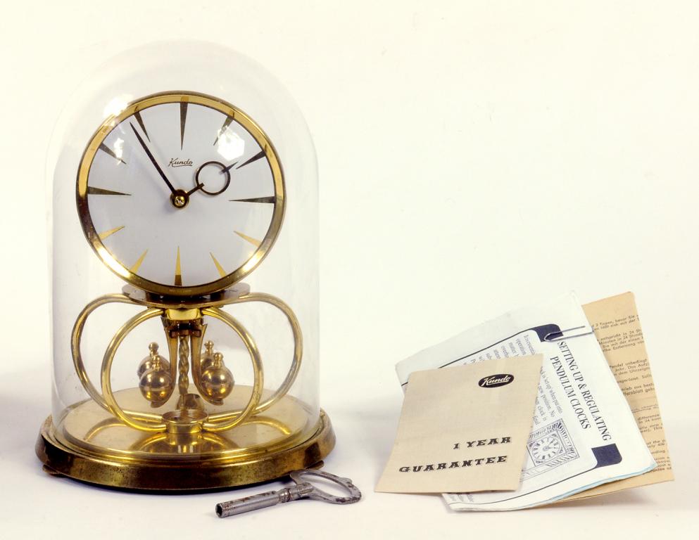 A KUNDO LACQUERED BRASS ANNIVERSARY CLOCK BENEATH GLASS DOME