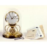 A KUNDO LACQUERED BRASS ANNIVERSARY CLOCK BENEATH GLASS DOME