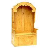 A WAXED PINE BOX SETTLE WITH PANELLED BACK AND ARCHED HOOD