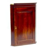 A GEORGE III MAHOGANY CORNER CUPBOARD WITH SHAPED SHELVES AND PANEL DOOR, 67CM W