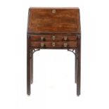 A GEORGE III MAHOGANY BUREAU having fitted interior, the flap with brass lock, the brass hinges